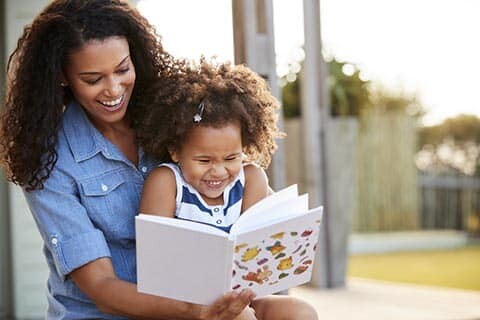 Mom reading children's book to young daughter.